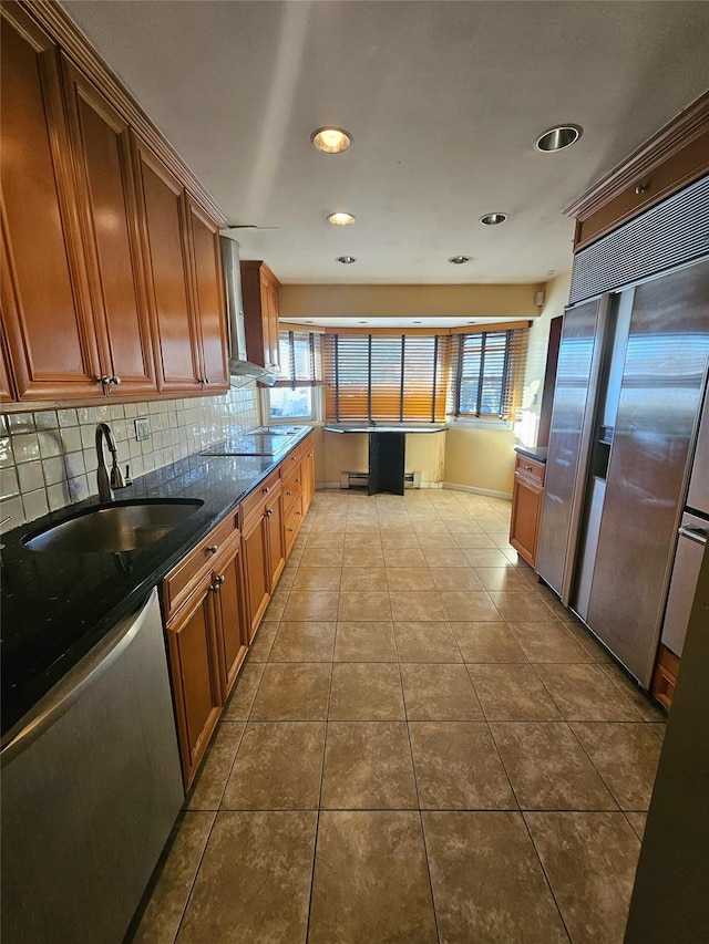 kitchen featuring tile patterned floors, stainless steel dishwasher, dark stone counters, a healthy amount of sunlight, and built in fridge