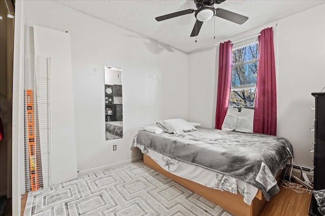 bedroom with ceiling fan, a baseboard radiator, a textured ceiling, and light wood-type flooring