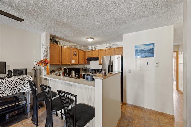 kitchen with kitchen peninsula, ceiling fan, sink, and stainless steel appliances