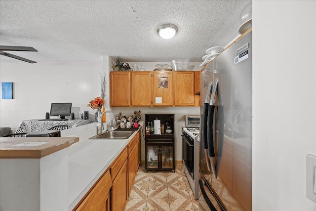 kitchen featuring ceiling fan, sink, stainless steel appliances, and a textured ceiling