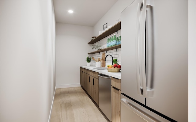 bar featuring decorative backsplash, sink, stainless steel appliances, and light hardwood / wood-style flooring