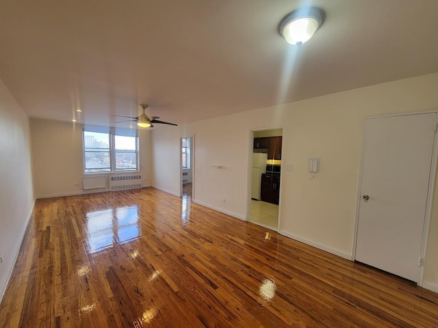 spare room featuring hardwood / wood-style floors, radiator, and ceiling fan