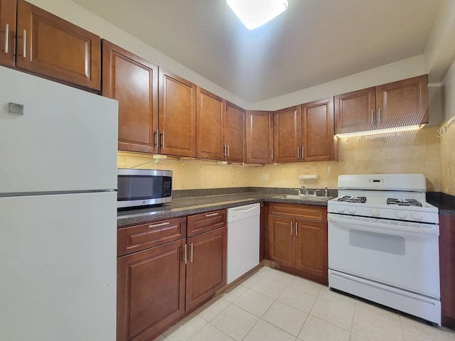 kitchen featuring light tile patterned floors, white appliances, and sink