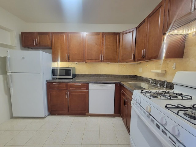 kitchen featuring sink, light tile patterned flooring, and white appliances