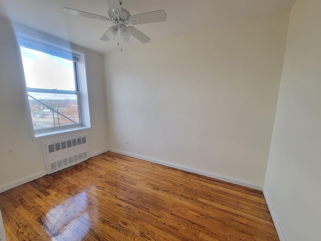 spare room with light wood-type flooring, radiator, and ceiling fan