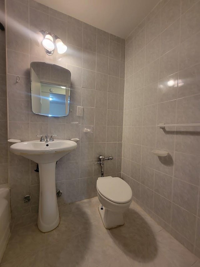 bathroom featuring tile patterned floors, toilet, and tile walls