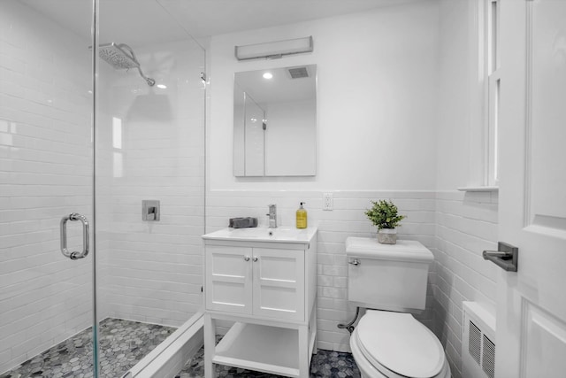 bathroom featuring toilet, vanity, tile walls, a shower with shower door, and radiator heating unit