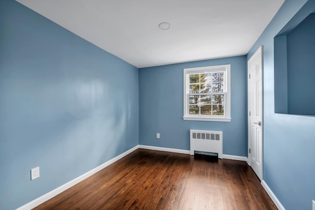 unfurnished room featuring radiator and dark wood-type flooring