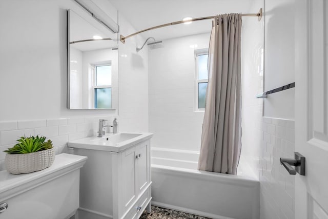 full bathroom featuring tile walls, toilet, vanity, and shower / tub combo