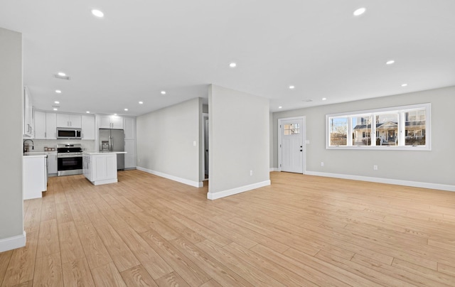 unfurnished living room with light hardwood / wood-style flooring and sink