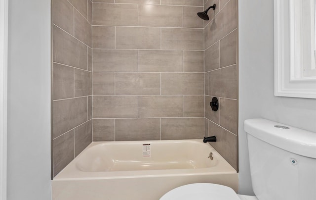 bathroom featuring tiled shower / bath combo and toilet