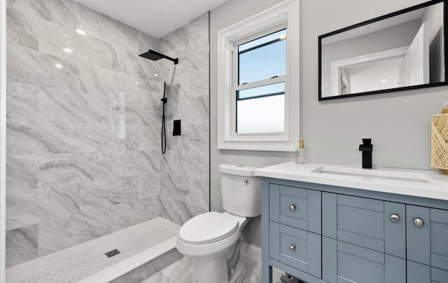 bathroom featuring a tile shower, vanity, and toilet