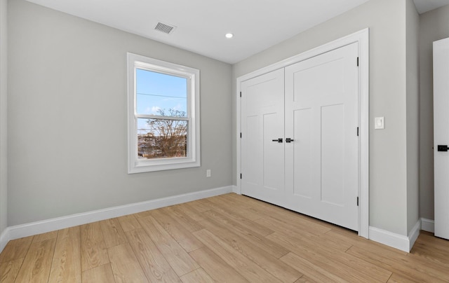 unfurnished bedroom with light hardwood / wood-style flooring and a closet