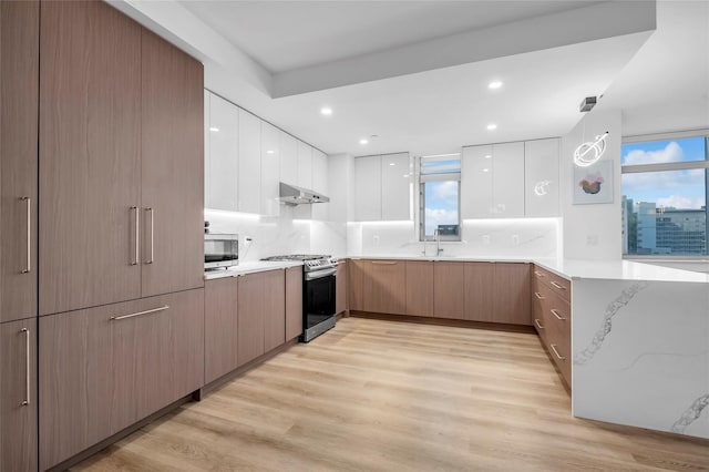 kitchen featuring white cabinets, appliances with stainless steel finishes, light hardwood / wood-style floors, sink, and backsplash