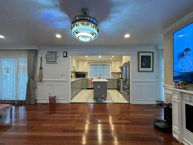 interior space featuring wood-type flooring, decorative backsplash, a kitchen island, gray cabinetry, and appliances with stainless steel finishes