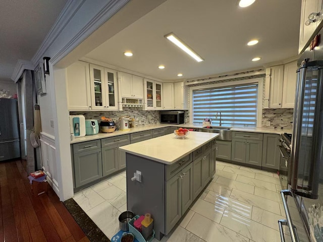 kitchen with stainless steel appliances, sink, white cabinetry, a center island, and gray cabinetry