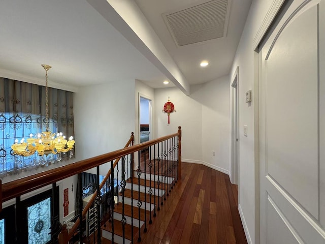 hall featuring dark wood-type flooring and an inviting chandelier