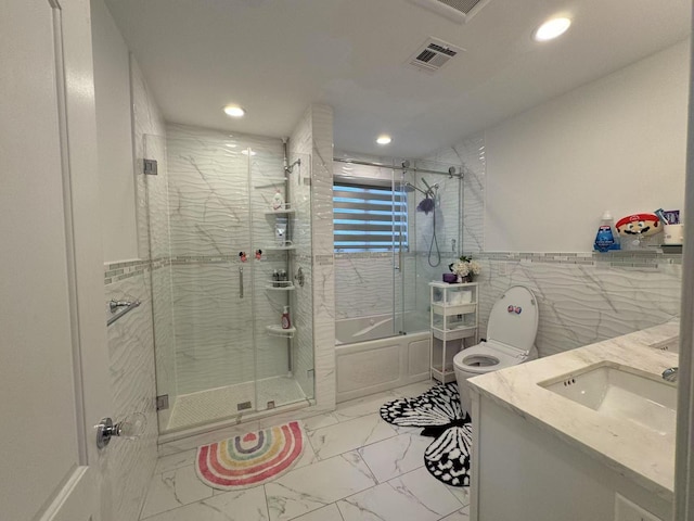 full bathroom with tile walls, enclosed tub / shower combo, toilet, and vanity