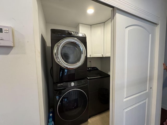 laundry area with cabinets, light tile patterned flooring, and stacked washer / dryer