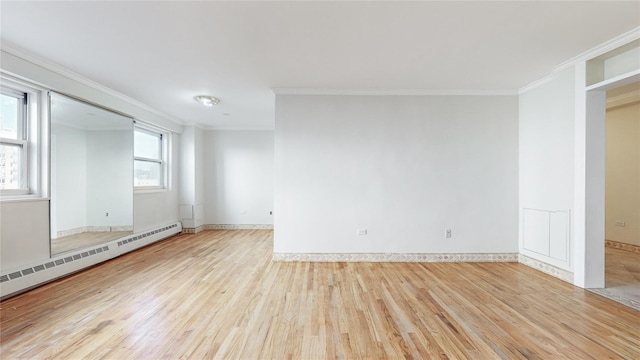 empty room with light wood-type flooring, baseboard heating, and crown molding