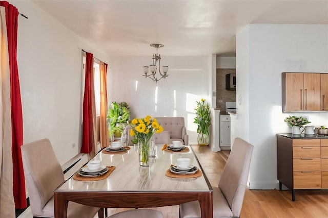 dining space with a baseboard radiator, a chandelier, and light hardwood / wood-style flooring