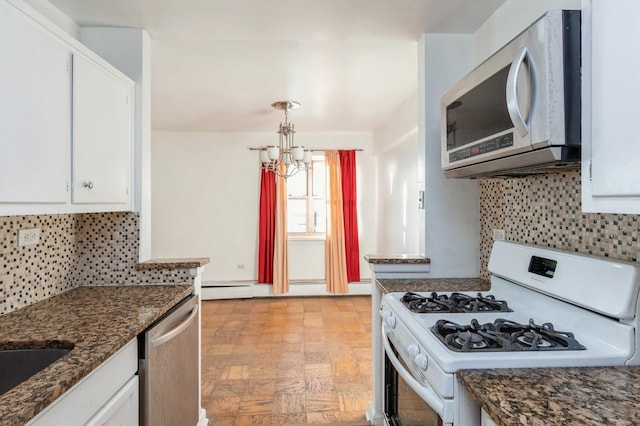 kitchen with backsplash, an inviting chandelier, white cabinetry, stainless steel appliances, and dark stone counters