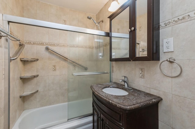 bathroom featuring combined bath / shower with glass door, vanity, and tile walls