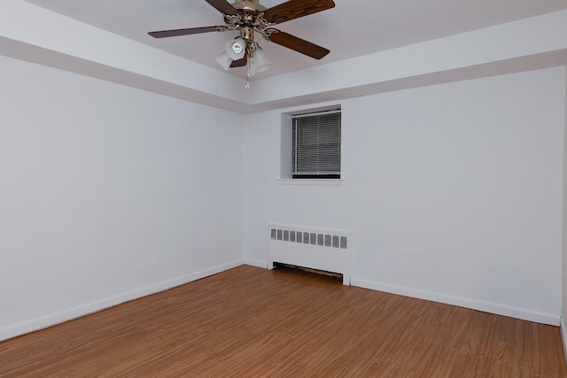 spare room featuring ceiling fan, radiator heating unit, and hardwood / wood-style floors