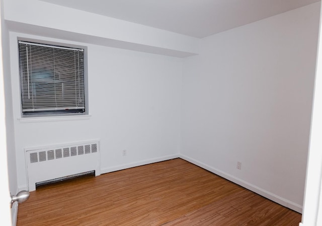 empty room with radiator and hardwood / wood-style floors