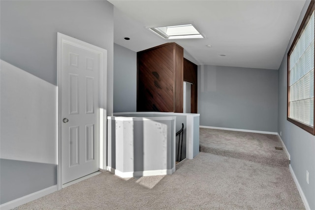 hallway featuring light carpet and a skylight