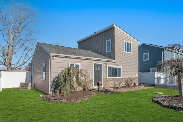 rear view of house featuring central air condition unit and a yard