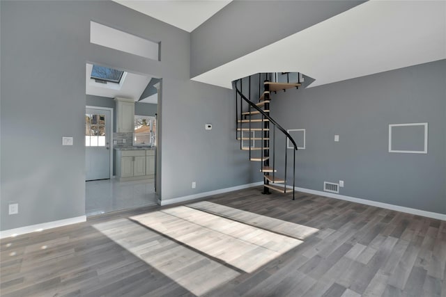 interior space with hardwood / wood-style floors and vaulted ceiling with skylight