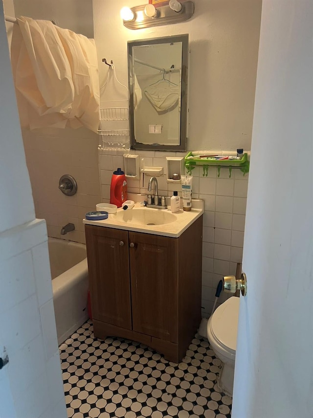 bathroom with toilet, vanity, shower / bathing tub combination, and tile walls