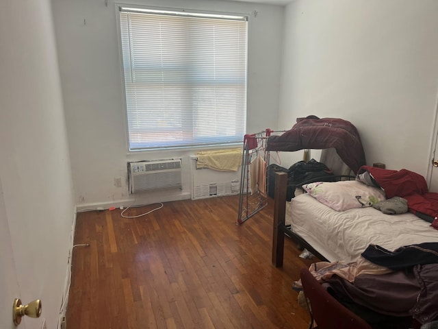 bedroom with baseboards, a wall mounted AC, and wood-type flooring