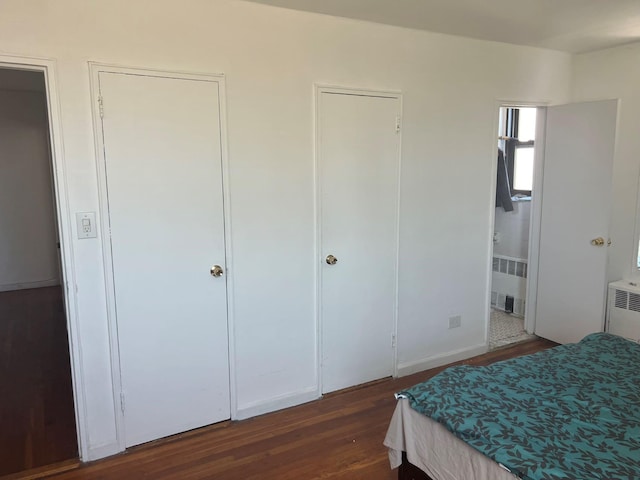 bedroom featuring radiator heating unit, ensuite bath, and wood finished floors