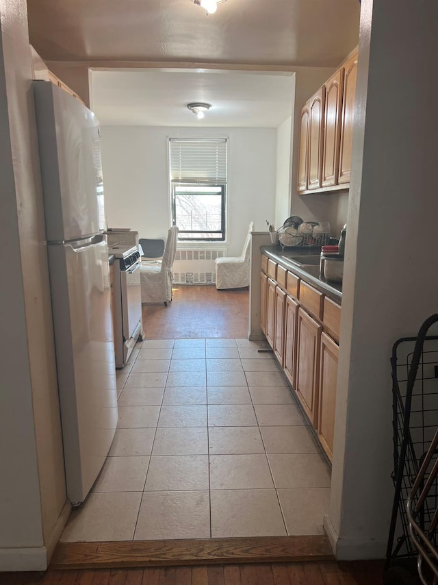 kitchen featuring light tile patterned flooring, dark countertops, a sink, and freestanding refrigerator