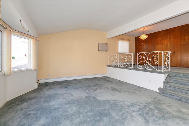 unfurnished living room featuring wooden walls, vaulted ceiling, dark colored carpet, a baseboard radiator, and a chandelier