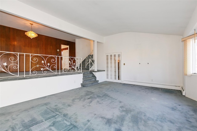 carpeted spare room with lofted ceiling, wood walls, and a baseboard heating unit