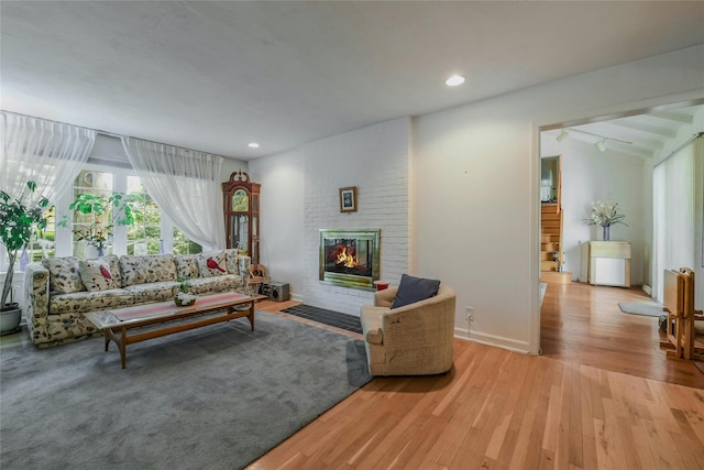 living room featuring light hardwood / wood-style flooring and a brick fireplace