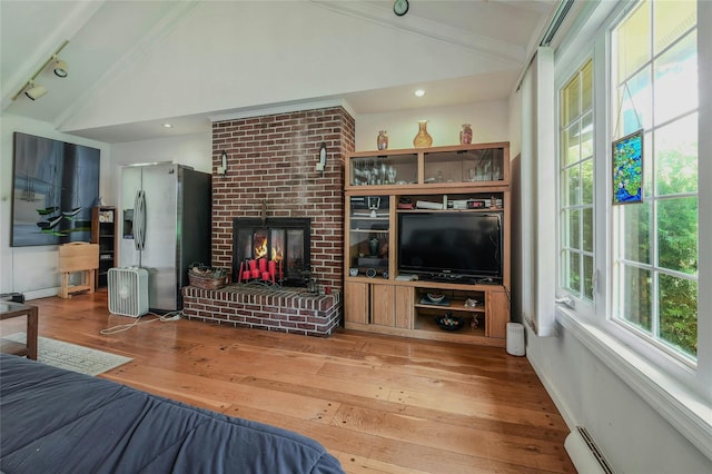 bedroom with a brick fireplace, stainless steel fridge with ice dispenser, a baseboard heating unit, wood-type flooring, and lofted ceiling