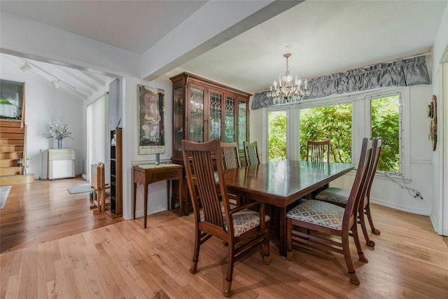 dining room with a chandelier, lofted ceiling, and light hardwood / wood-style flooring