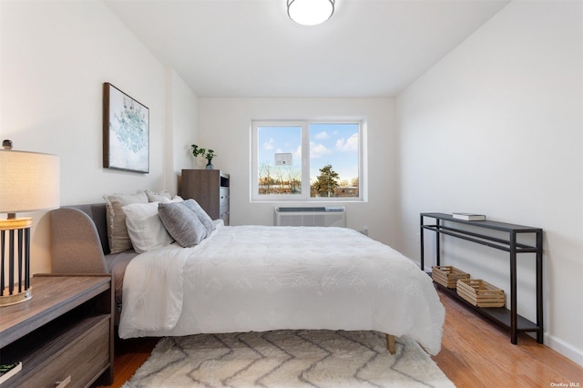 bedroom with light hardwood / wood-style flooring and a wall mounted AC