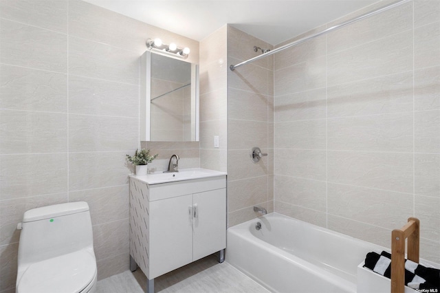 full bathroom with tiled shower / bath, vanity, tile walls, and toilet