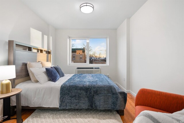 bedroom with a wall mounted AC and wood-type flooring