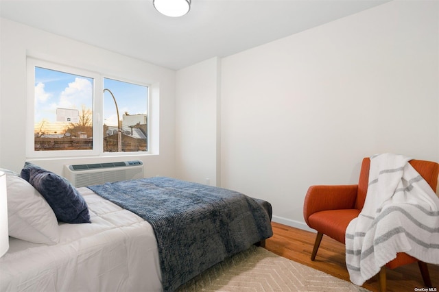 bedroom with a wall mounted air conditioner and hardwood / wood-style floors