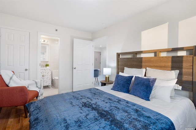 bedroom with wood-type flooring and connected bathroom