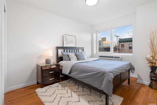 bedroom featuring light hardwood / wood-style flooring and a wall mounted AC