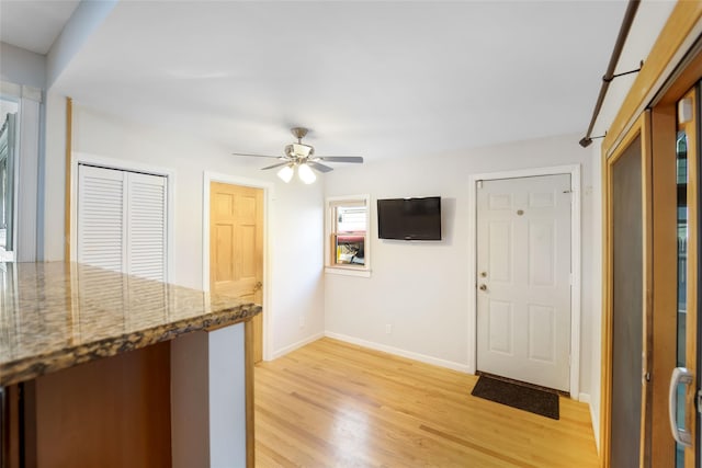 kitchen featuring ceiling fan, light wood-type flooring, and stone countertops