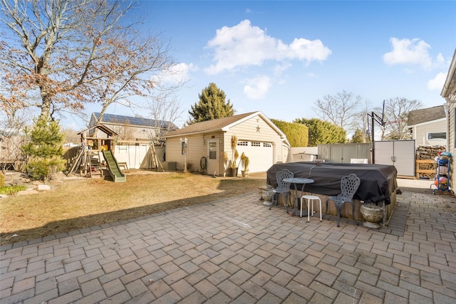 view of patio featuring a playground, a garage, and an outdoor structure