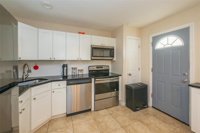 kitchen featuring sink, tasteful backsplash, light tile patterned flooring, white cabinets, and appliances with stainless steel finishes